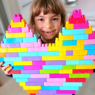 Copil lângă o inimă mare construită din piese colorate
