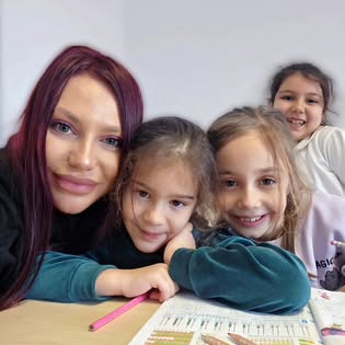 Un cadru cald: educatoarea alături de două fetițe zâmbitoare